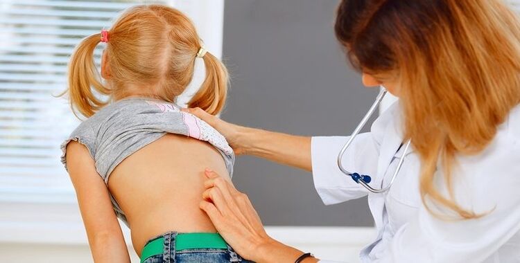 doctor examining the back of a child with back pain